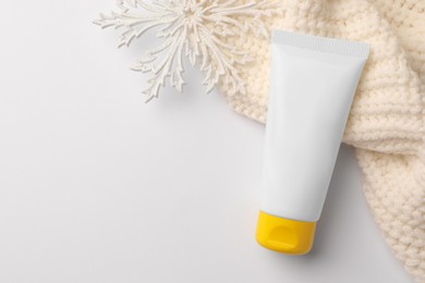 Winter skin care. Hand cream, decorative snowflake and knitted sweater on white background, top view. Space for text