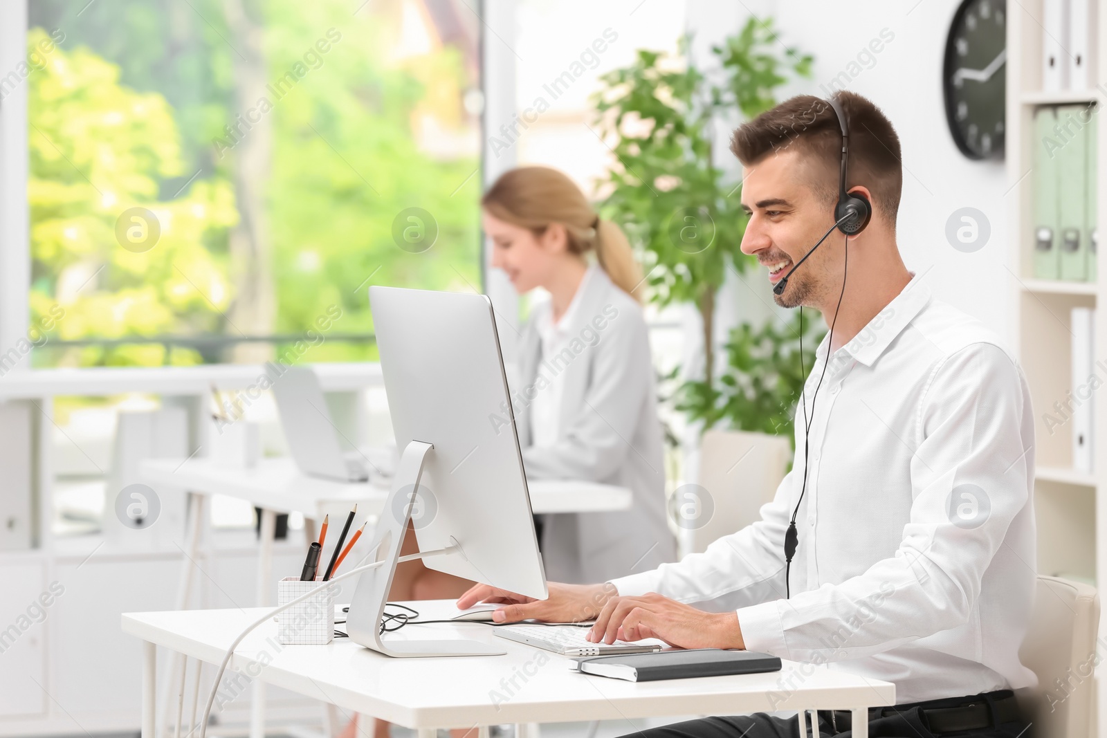 Photo of Male receptionist with headset at desk in office