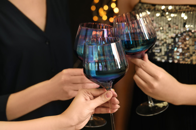 Women clinking glasses of red wine at party, closeup