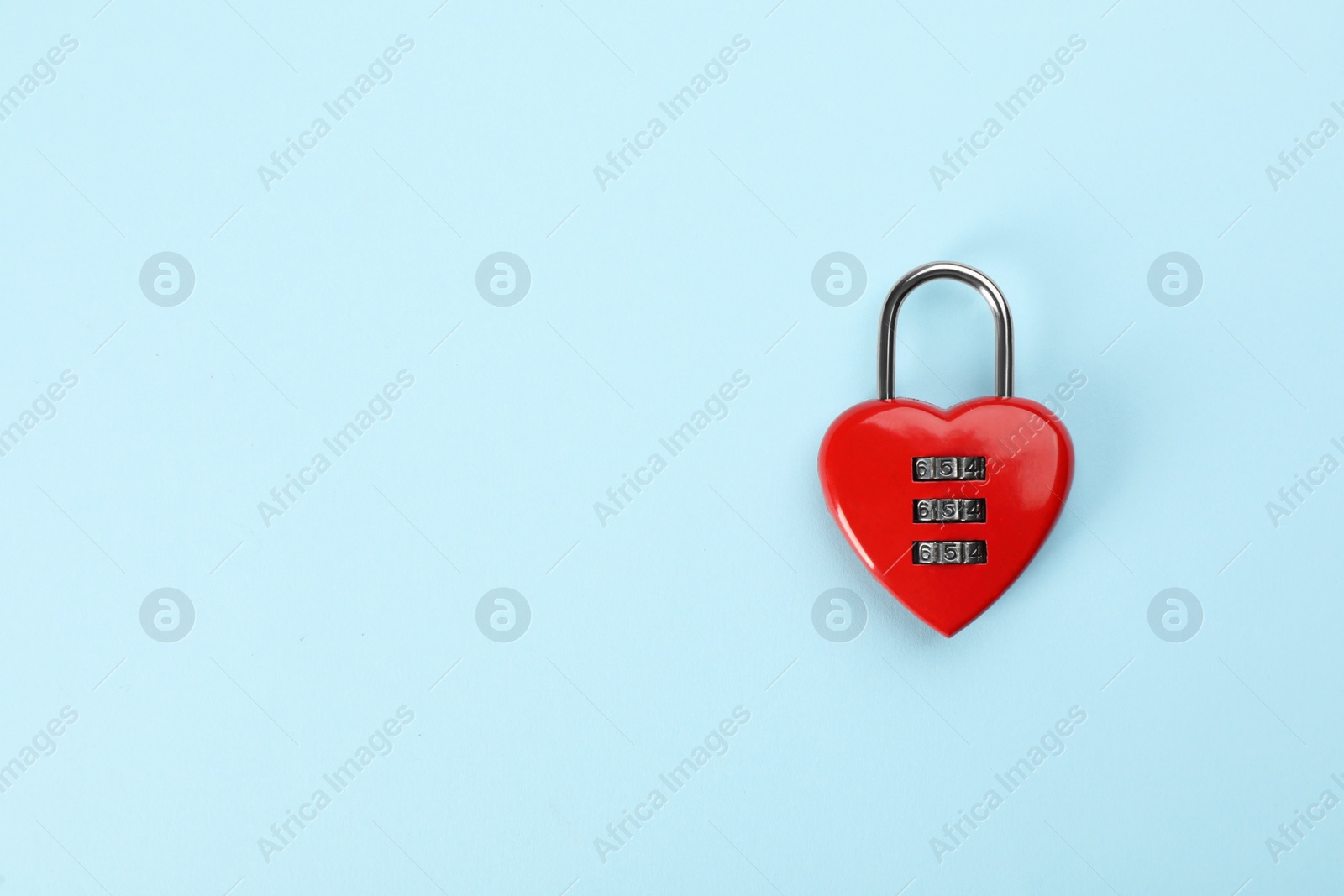 Photo of Red heart shaped combination lock on light blue background, top view. Space for text