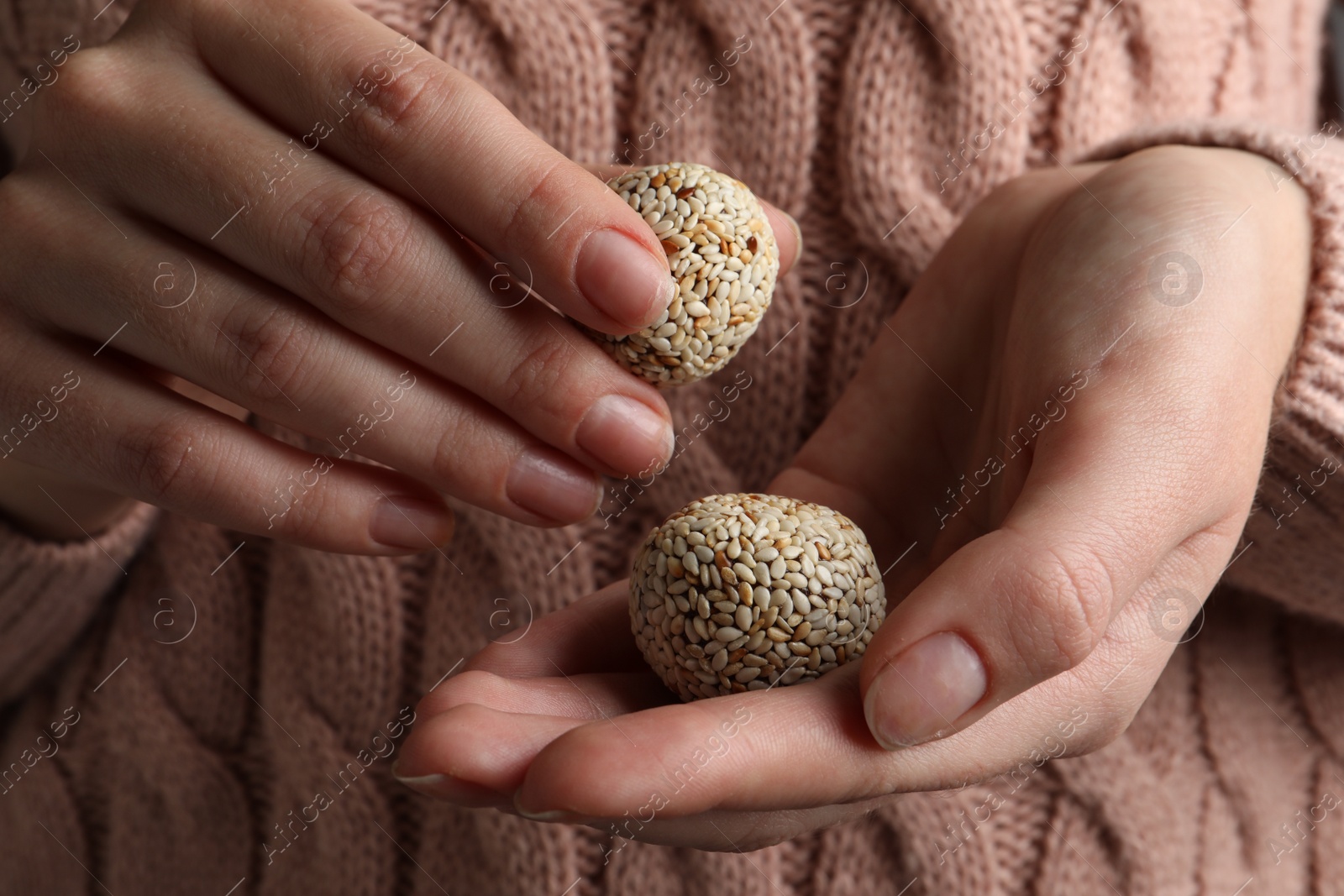Photo of Woman holding delicious vegan candy balls with sesame seeds, closeup