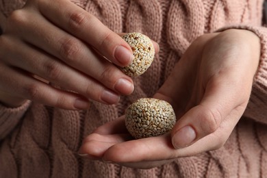 Photo of Woman holding delicious vegan candy balls with sesame seeds, closeup