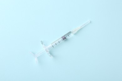 Photo of Injection cosmetology. One medical syringe on light blue background, top view