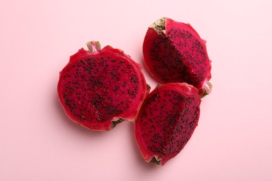 Photo of Delicious cut red pitahaya fruit on light pink background, flat lay
