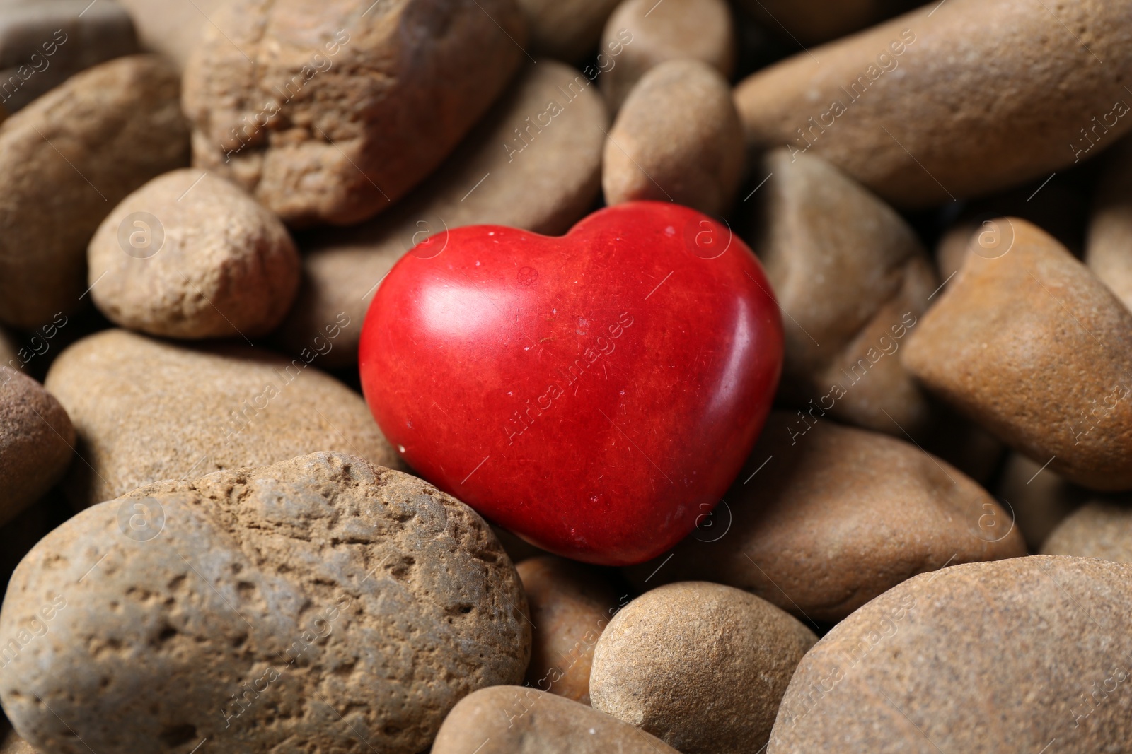 Photo of One red decorative heart on stones, closeup