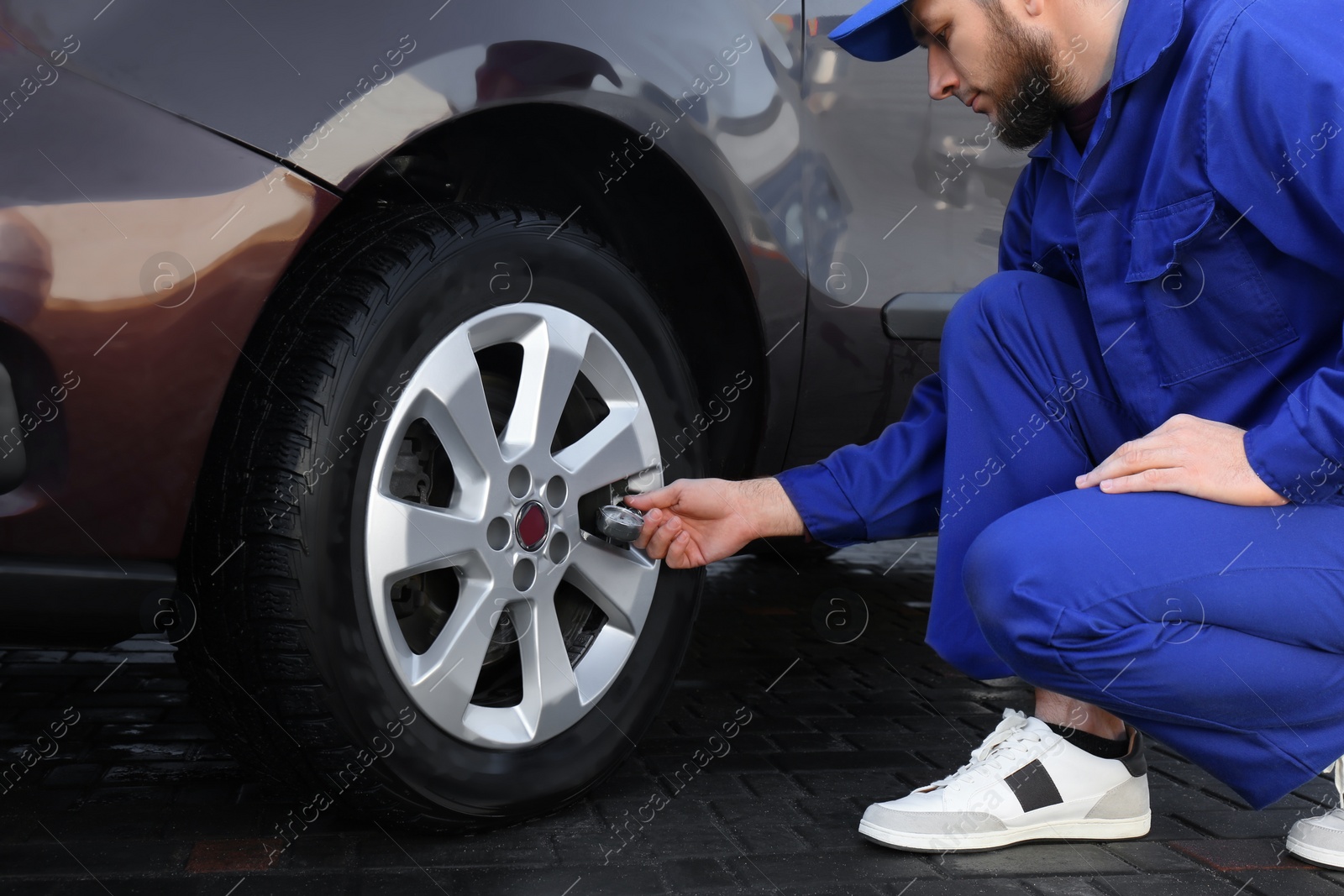 Photo of Mechanic checking tire air pressure at car service