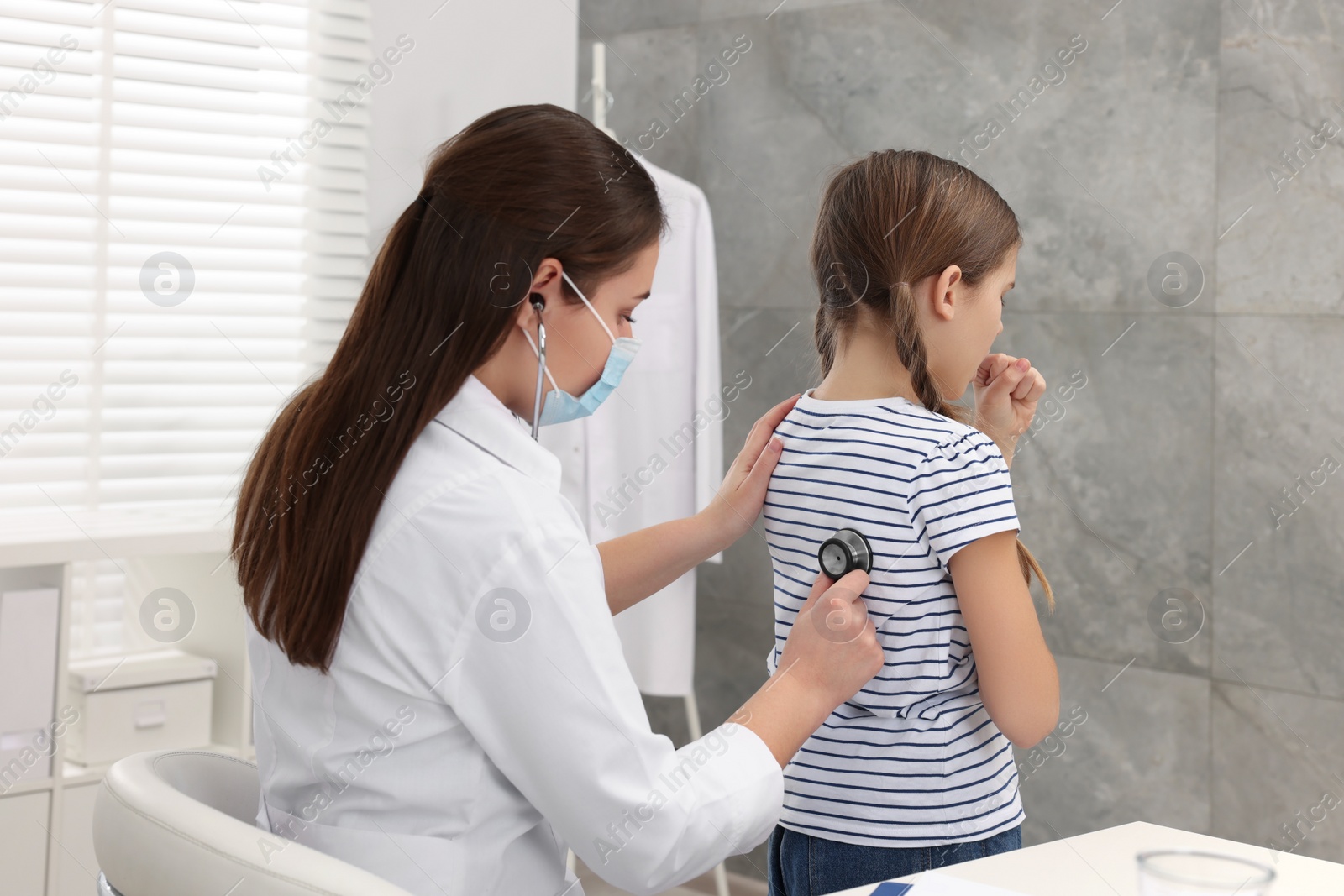 Photo of Doctor examining coughing girl in hospital. Cold symptoms