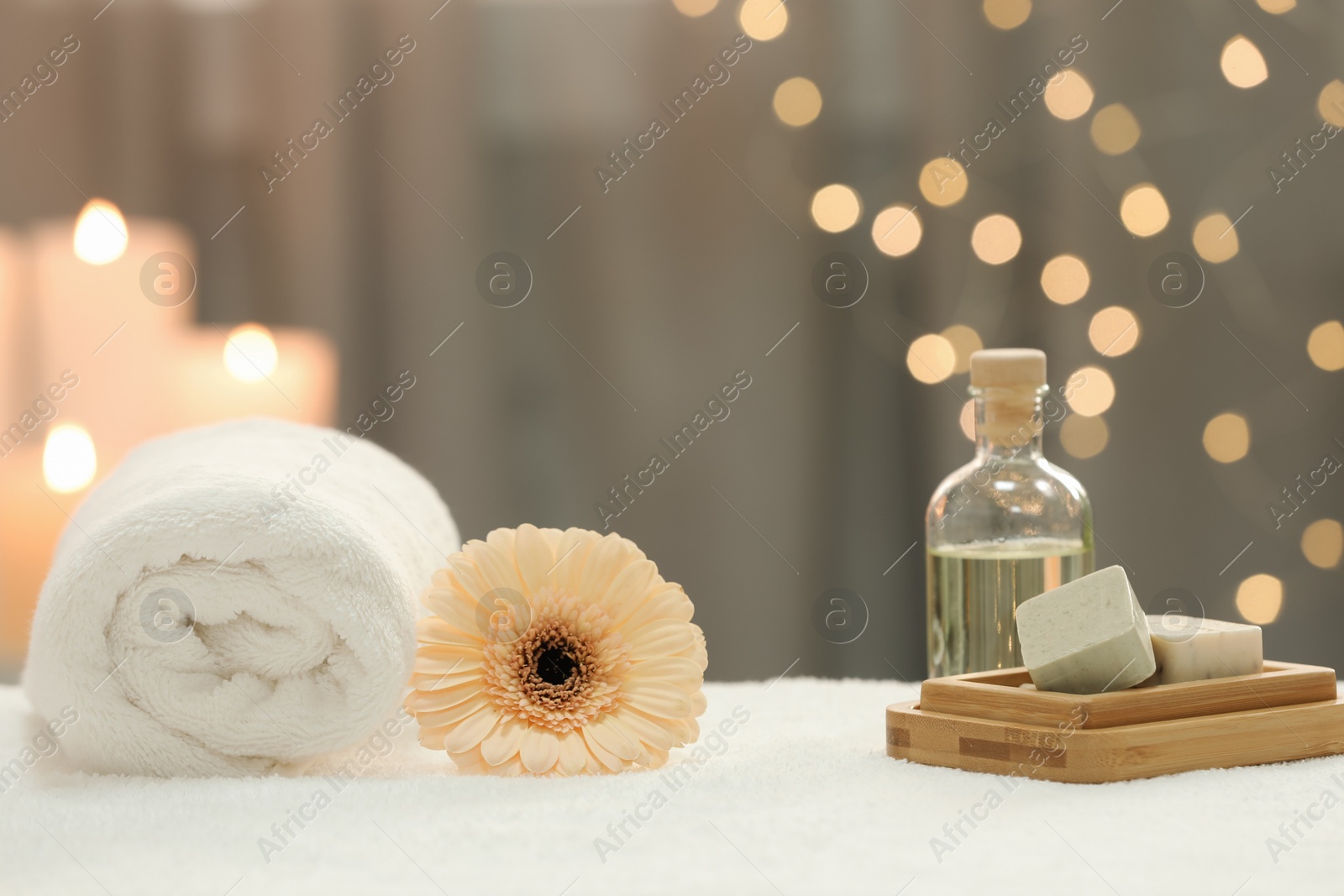 Photo of Beautiful composition with different spa products and flower on white towel against blurred lights