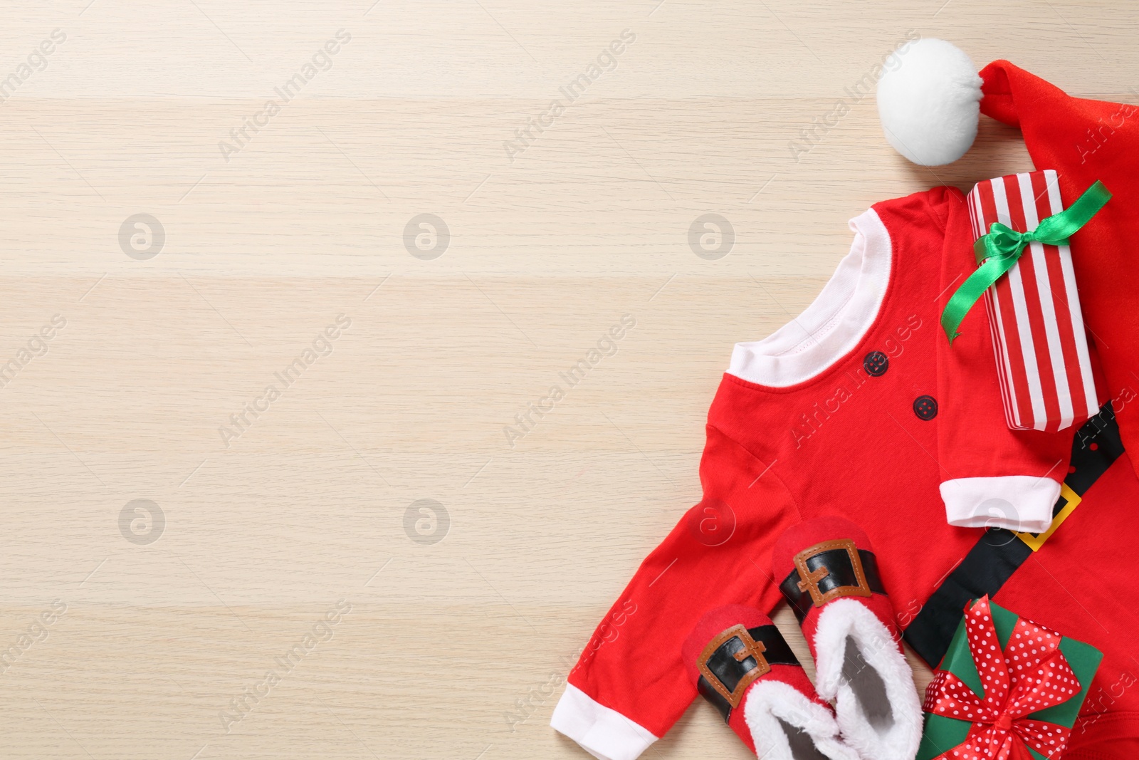 Photo of Flat lay composition with Christmas baby outfit on wooden background. Space for text