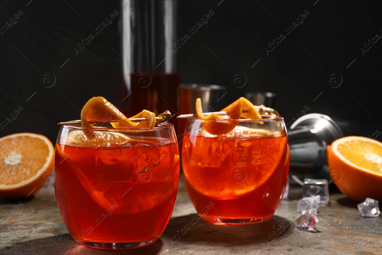 Photo of Aperol spritz cocktail, ice cubes and orange slices in glasses on grey textured table, closeup