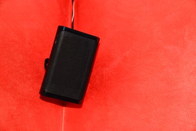 Photo of Modern audio speaker on red wall. Space for text