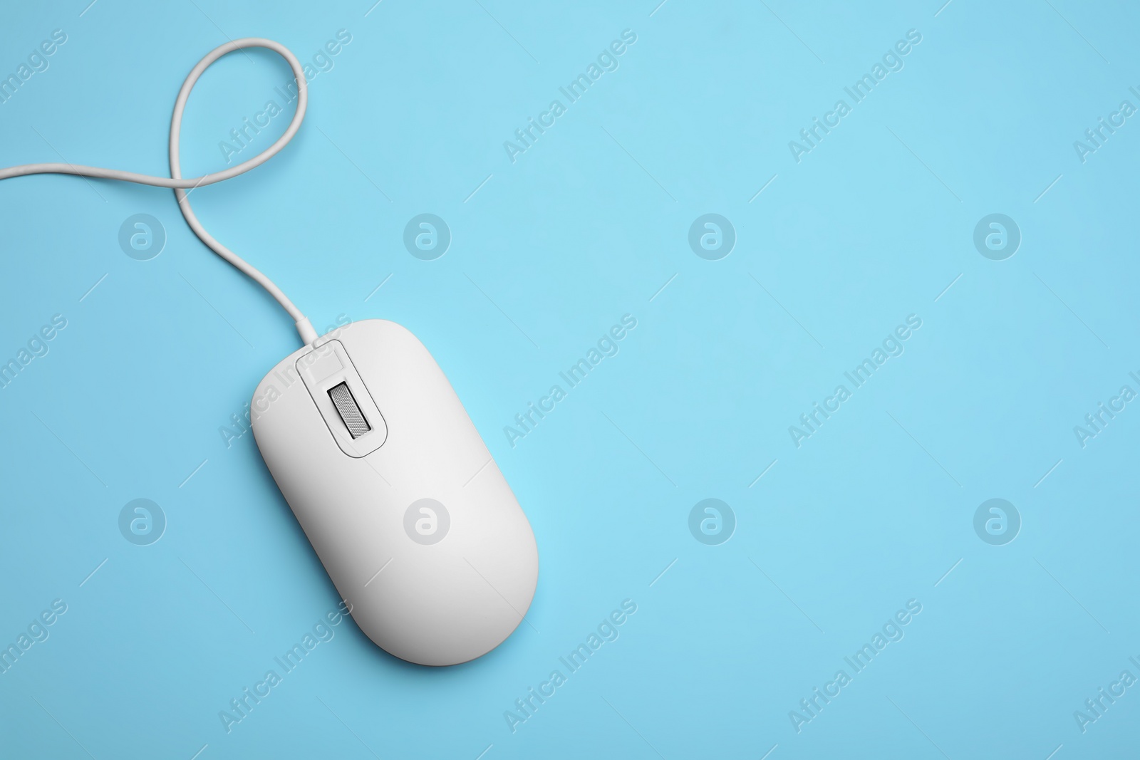 Photo of Wired computer mouse on light blue background, top view. Space for text