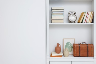 Books and different decorative elements on shelving unit indoors, space for text