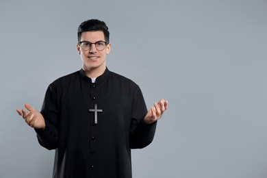 Photo of Priest wearing cassock with clerical collar on grey background. Space for text