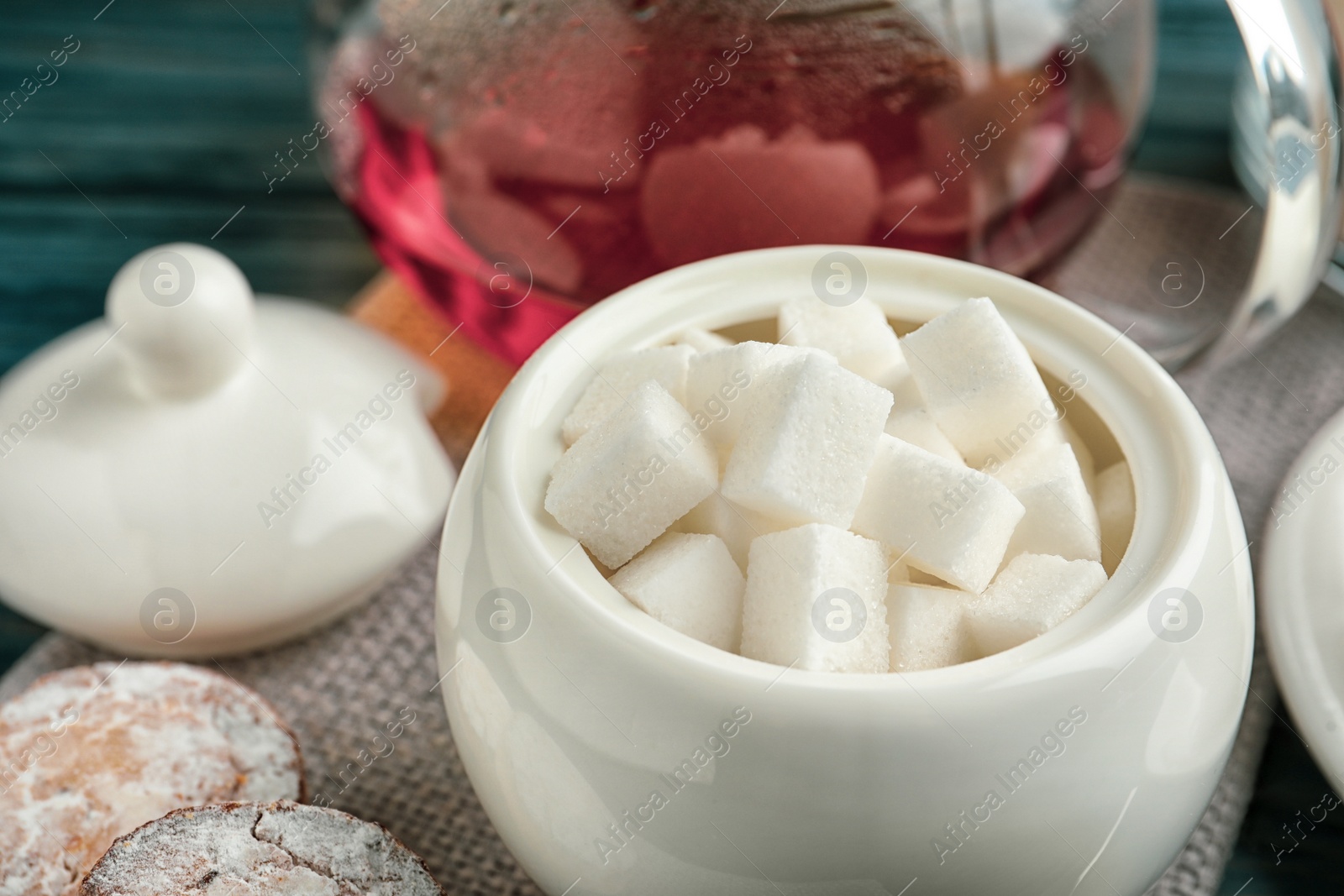 Photo of Refined sugar cubes in ceramic bowl on table, closeup