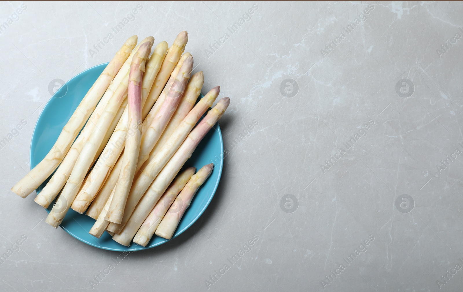 Photo of Fresh white asparagus on grey marble table, top view. Space for text