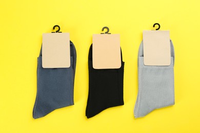 Photo of Soft cotton socks on yellow background, flat lay