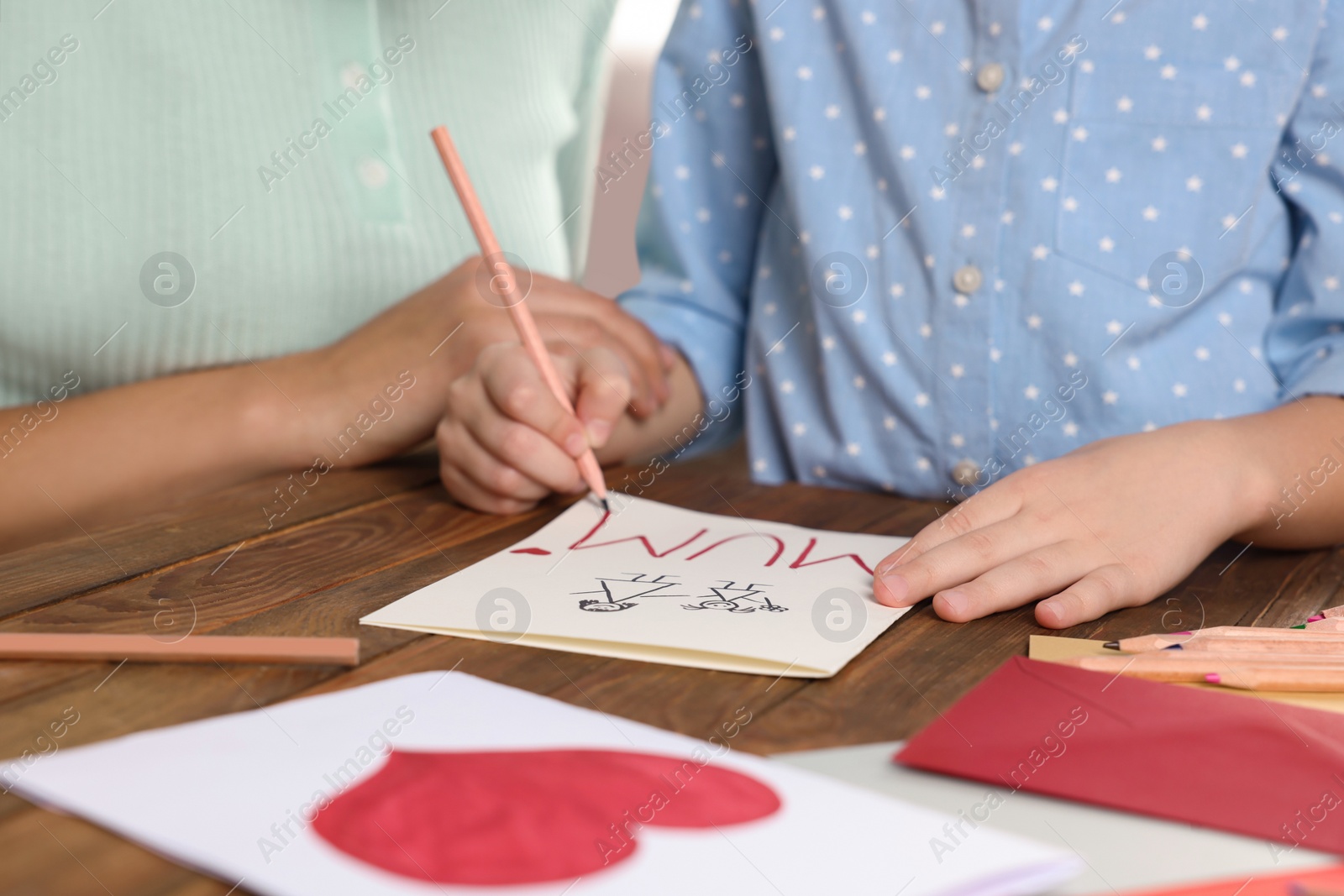 Photo of Little girl with her mother making beautiful greeting card at home, closeup