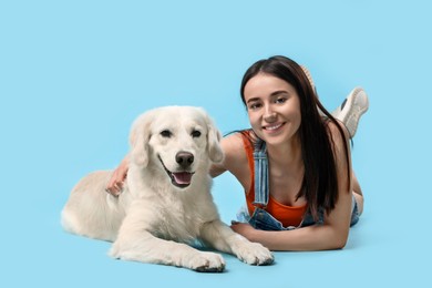 Photo of Happy woman with cute Labrador Retriever dog on light blue background. Adorable pet