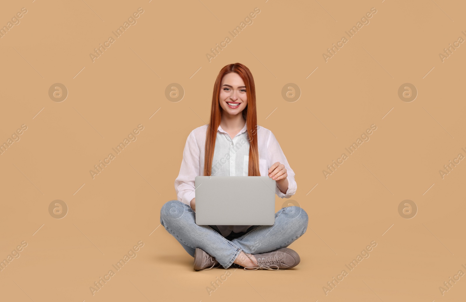 Photo of Smiling young woman with laptop on beige background