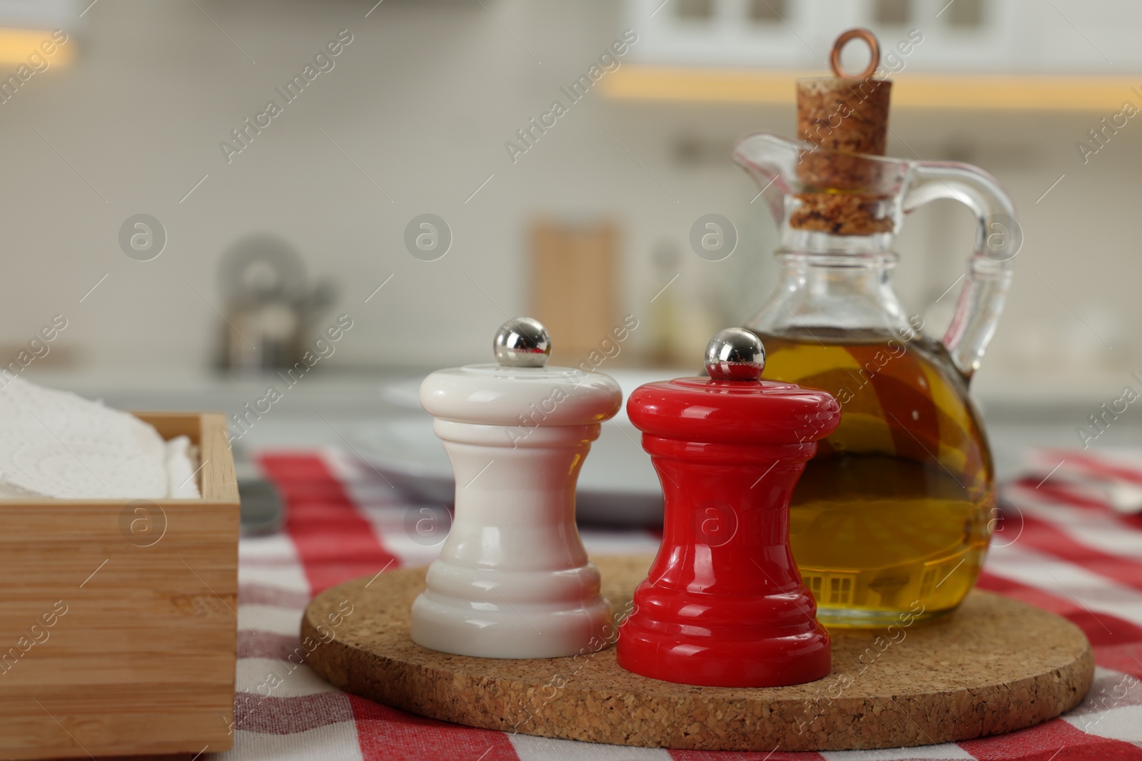 Photo of Ceramic salt and pepper mills with bottle of oil on kitchen table