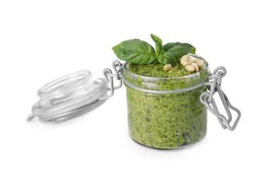 Photo of Delicious pesto sauce, pine nuts and basil leaves in jar isolated on white