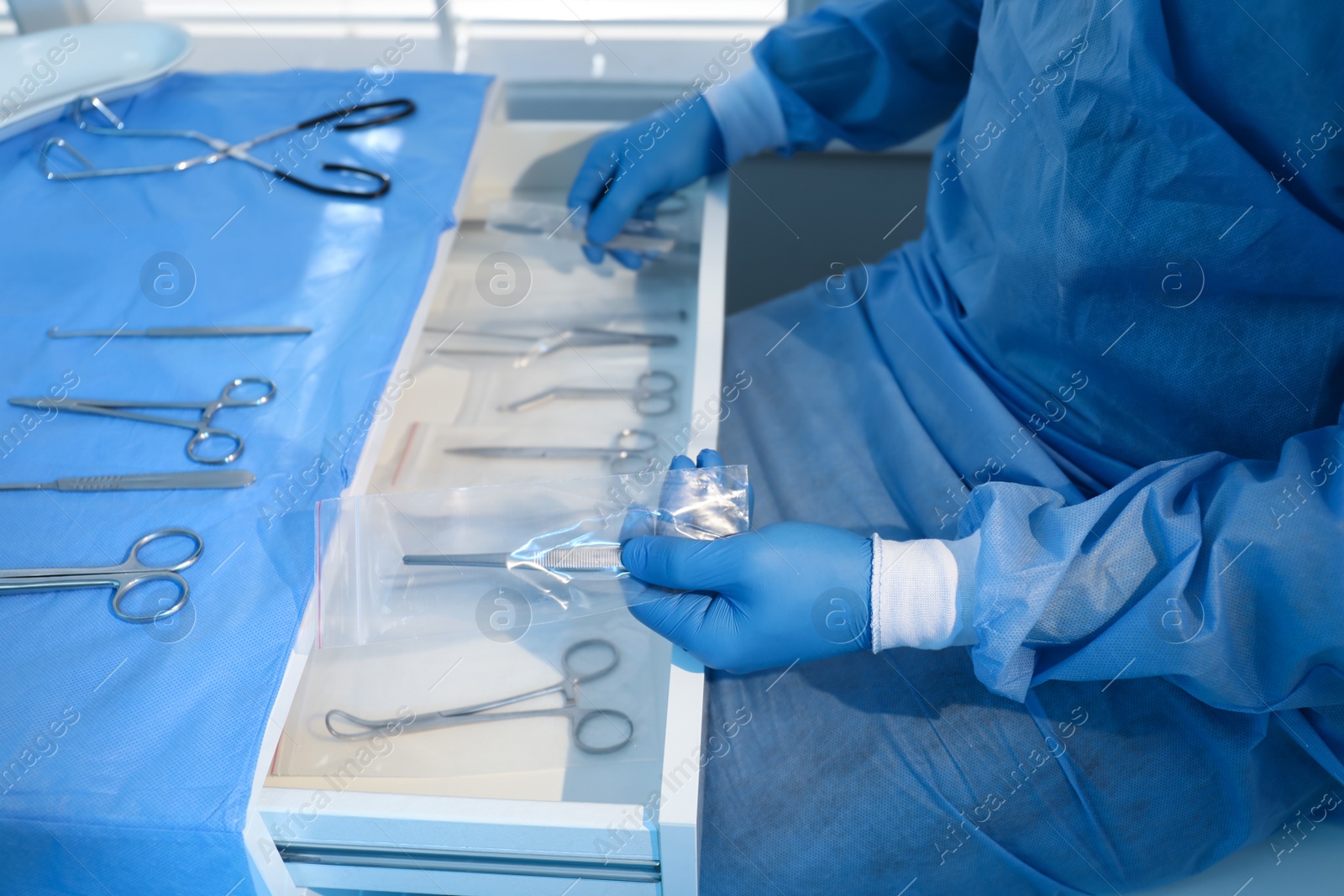 Photo of Doctor putting medical forceps into drawer indoors, closeup. Table with different surgical instruments