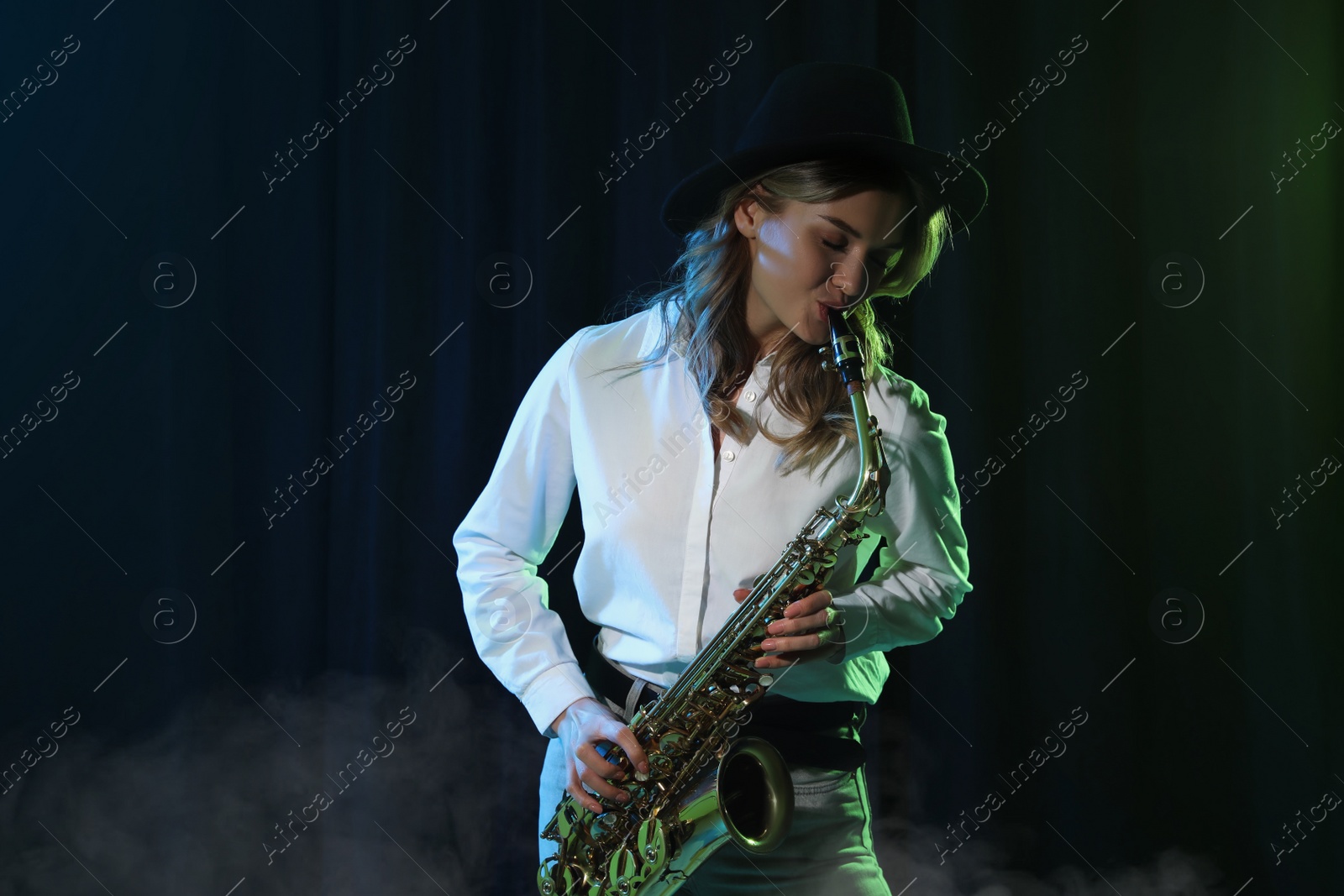 Photo of Beautiful young woman playing saxophone on dark background