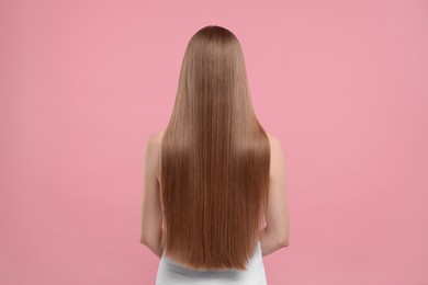 Woman with healthy hair on pink background, back view