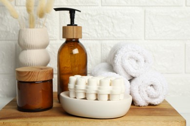 Photo of Different bath accessories, personal care products and spikelets in vase on table near white brick wall, closeup