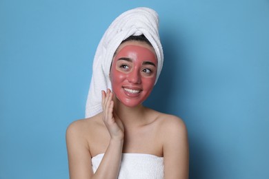 Photo of Woman with pomegranate face mask on light blue background