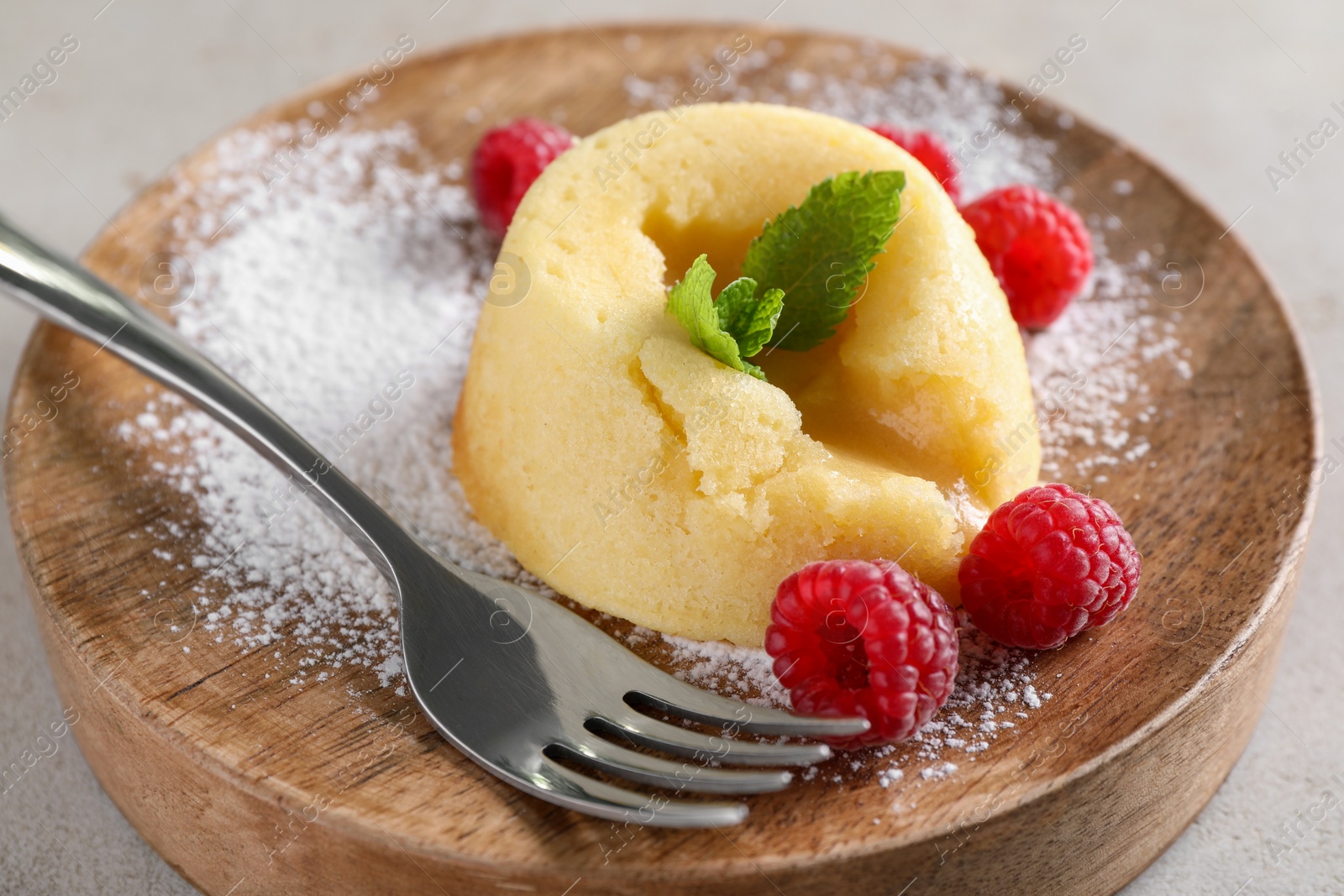 Photo of Tasty vanilla fondant with white chocolate and raspberries on table, closeup