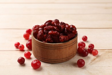 Photo of Dried cranberries in bowl and fresh berries on wooden table