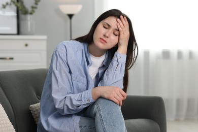 Photo of Overwhelmed woman sitting on sofa at home