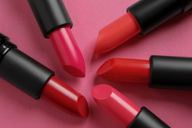 Beautiful lipsticks on pink background, flat lay