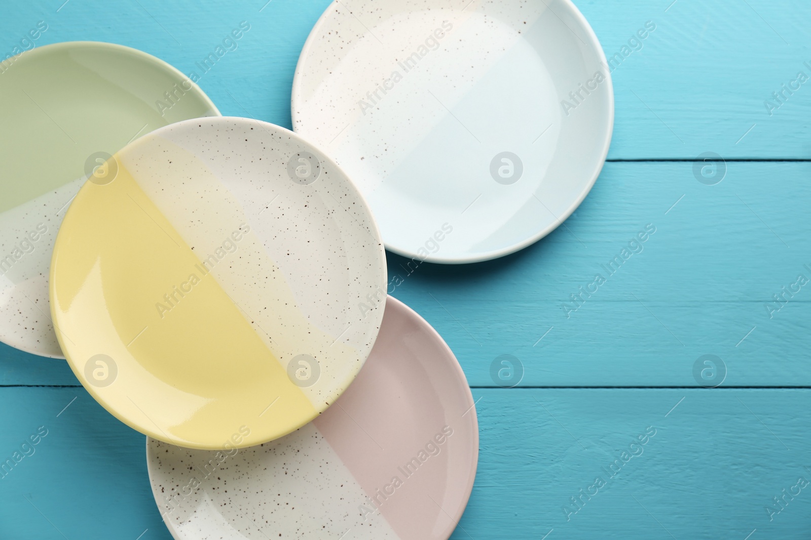 Photo of Beautiful ceramic plates on light blue wooden table, flat lay. Space for text