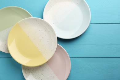 Beautiful ceramic plates on light blue wooden table, flat lay. Space for text
