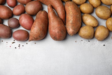 Different types of fresh potatoes on light gray table, flat lay. Space for text