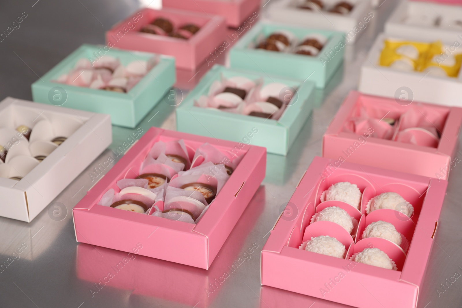 Photo of Many delicious candies in boxes on table. Production line