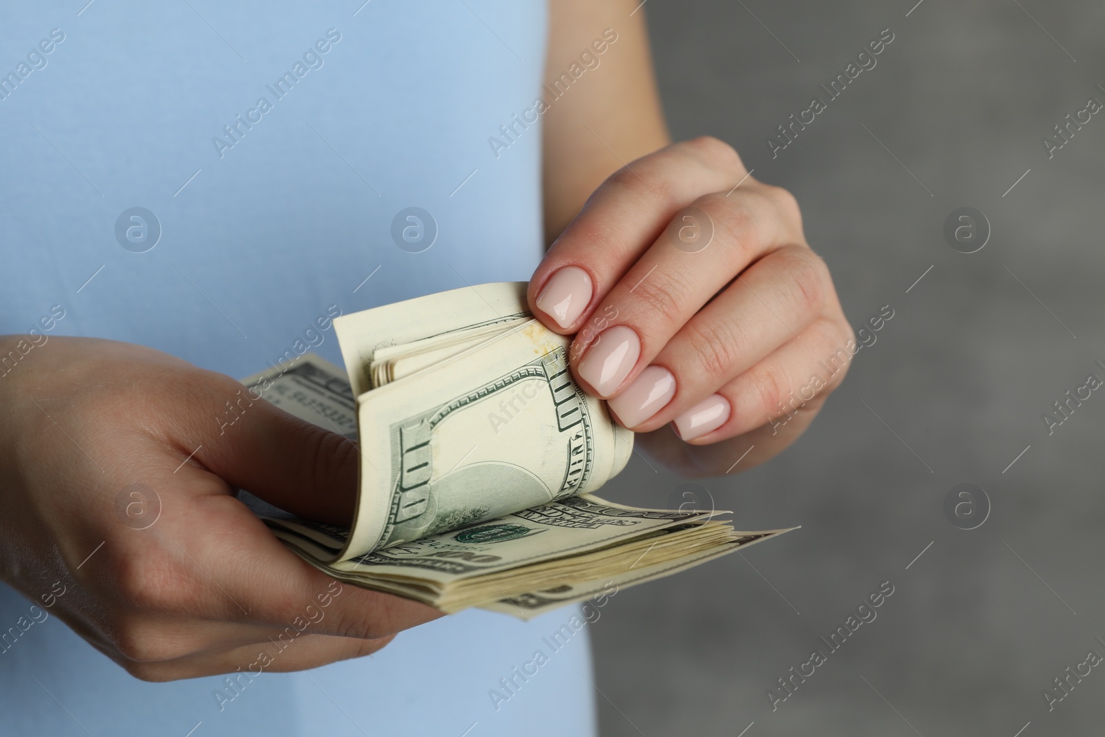 Photo of Money exchange. Woman counting dollar banknotes on grey background, closeup