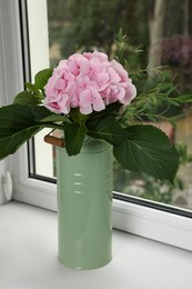 Photo of Beautiful blooming pink hortensia in can on window sill indoors