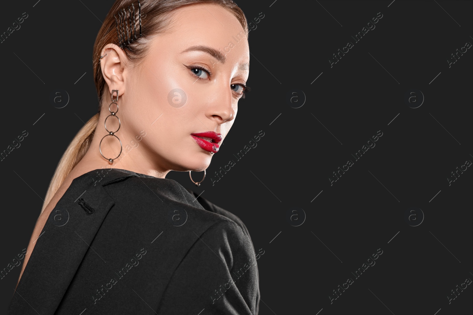 Photo of Young woman with lip and ear piercings on black background, space for text