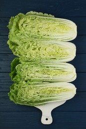 Photo of Cut fresh ripe Chinese cabbages on blue wooden table, flat lay