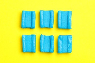 Blue bubble gums on yellow background, flat lay