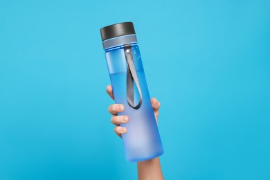 Photo of Woman holding bottle of drink on light blue background, closeup