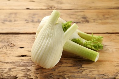 Photo of Fresh raw fennel bulbs on wooden table, closeup