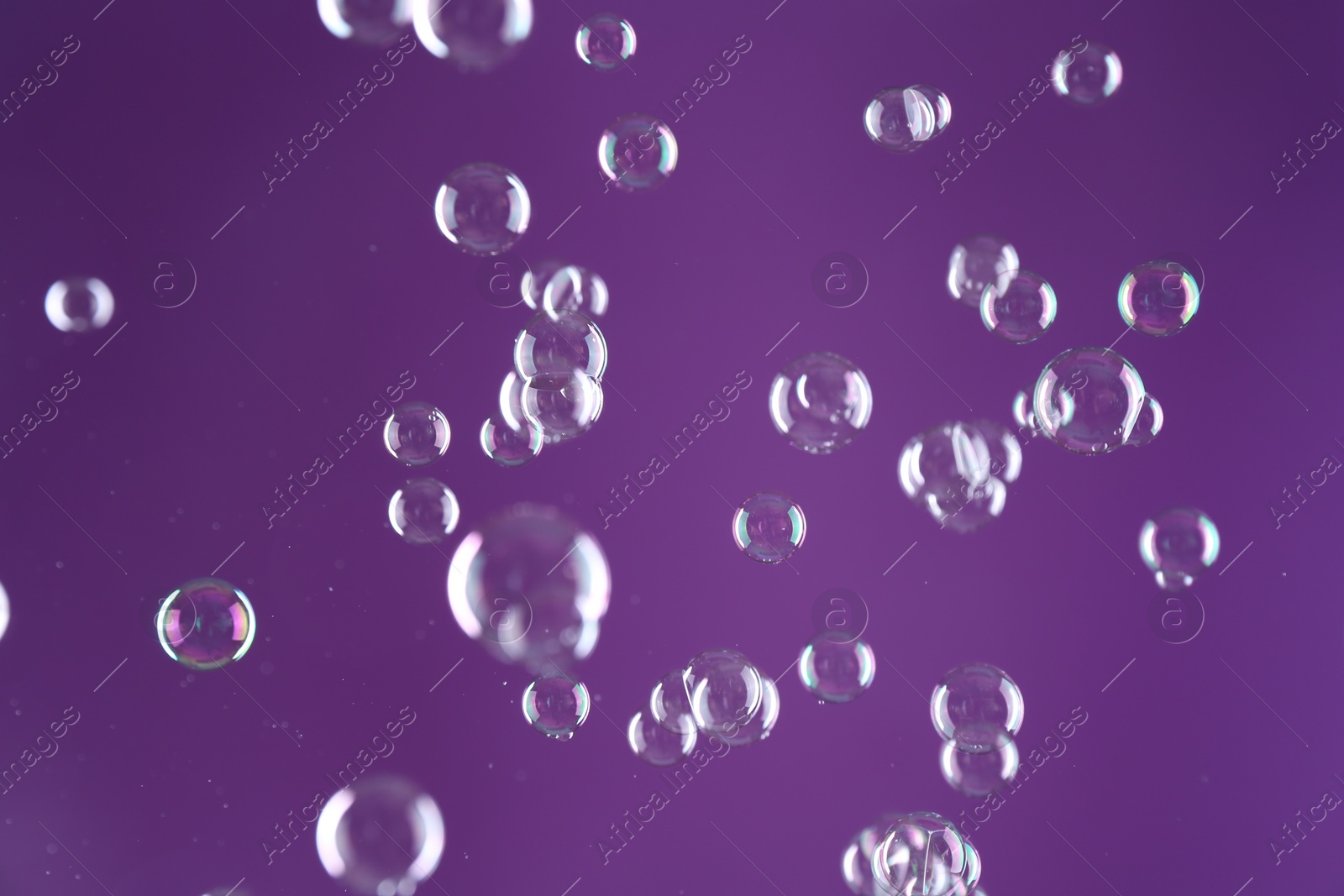 Photo of Beautiful transparent soap bubbles on purple background