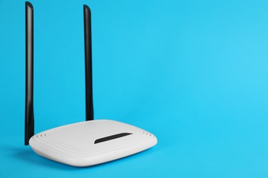 Photo of Modern Wi-Fi router on light blue background. Space for text