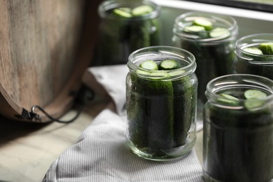 Glass jars with fresh cucumbers on wooden table, closeup. Space for text