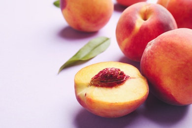 Photo of Fresh ripe peaches on violet background, closeup. Space for text
